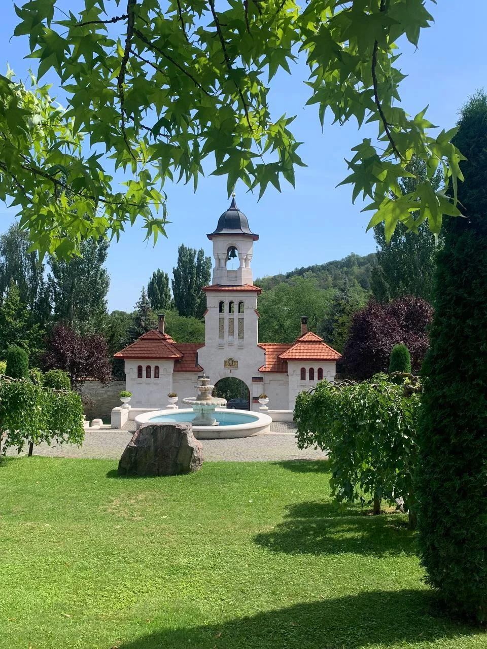 Curchi Monastery white stone church with bell tower surrounded by green lawn and lush vegetation