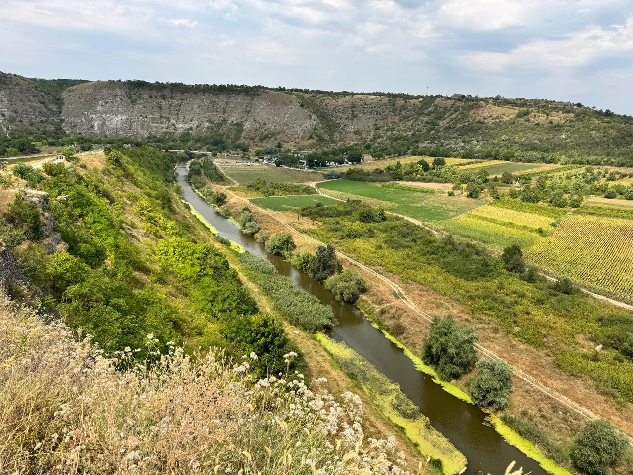 Panoramic view of a river valley with limestone cliffs, agricultural fields, and scattered settlements in Moldova