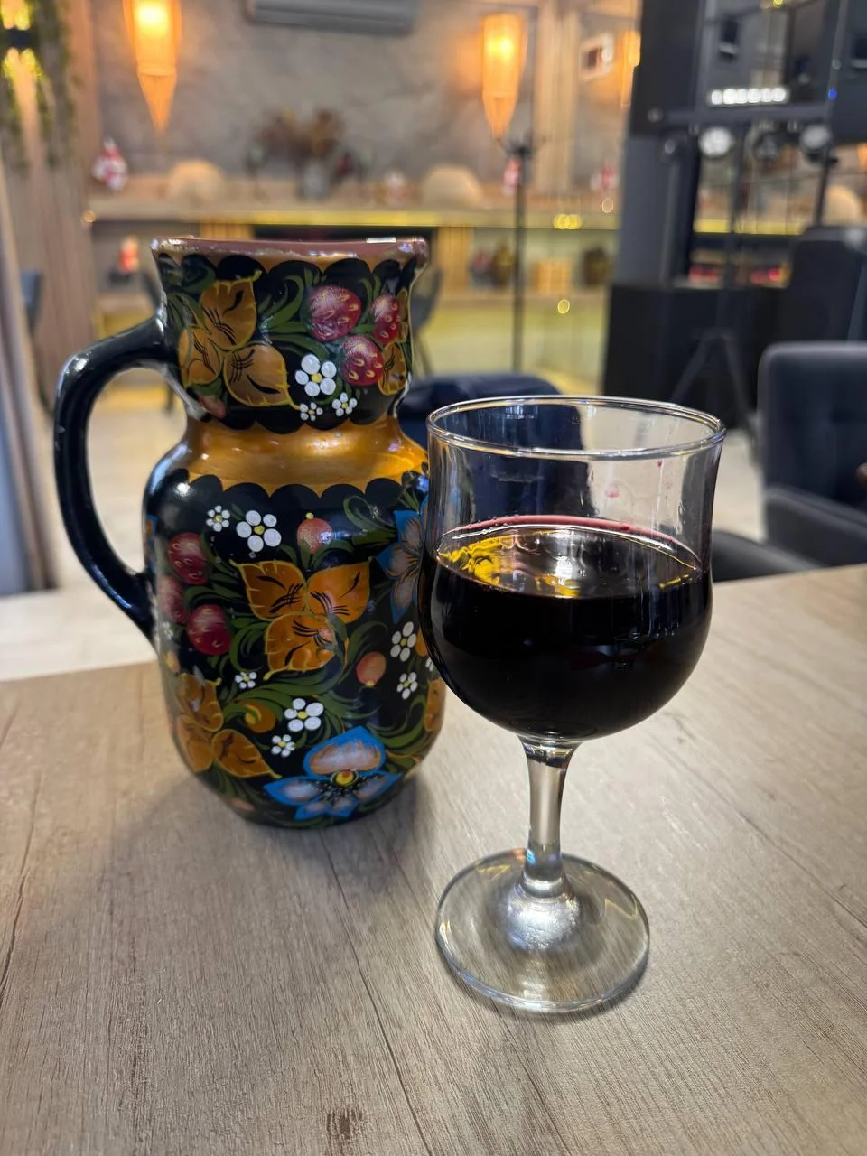 Traditional Moldovan ceramic pitcher with red wine in a glass on a wooden table